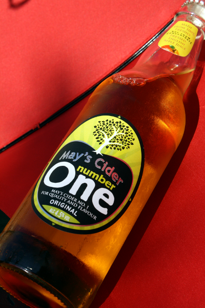 bottle of mays cider number one by the amazing cider company with a red background behind it